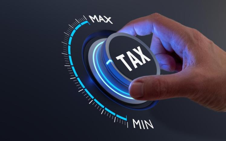 Image depicting a hand turning a tax dial between min and max.